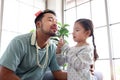 Joyful father playing with his little adorable daughter together, girl doing makeup to her dad by cosmetic, sitting on sofa in Royalty Free Stock Photo