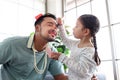 Joyful father playing with his little adorable daughter together, girl doing makeup to her dad by cosmetic, sitting on sofa in Royalty Free Stock Photo