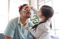 Joyful father playing with his little cute daughter together, girl doing makeup to her dad by cosmetic during sitting on sofa in Royalty Free Stock Photo