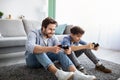 Joyful father and son competing in online video games, using joysticks, having fun at home. Royalty Free Stock Photo