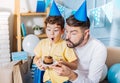 Joyful father and son enthusiastically blowing out birthday candle