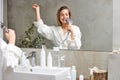 joyful caucasian female in bathrobe has fun in bathroom, singing Royalty Free Stock Photo