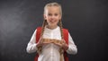 Joyful female child holding wooden cubes with school word, first-former kid