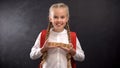 Joyful female child holding wooden cubes with school word, first-former kid