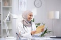 Joyful female doctor in hijab received envelope message mail notification with good results of patient's treatment