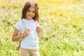 Joyful female kid walking on grassland with rucksack Royalty Free Stock Photo
