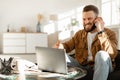 Joyful Freelancer Man Talking On Phone Using Laptop At Home Royalty Free Stock Photo