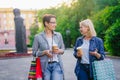 Joyful friends walking in street holding to go coffee and shopping bags talking Royalty Free Stock Photo