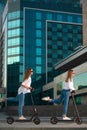 Beautiful young women is enjoying sunny summer day while riding around the city on electro kick scooters. Lifestyle. Royalty Free Stock Photo