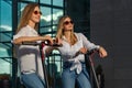 Beautiful young women is enjoying sunny summer day while riding around the city on electro kick scooters. Lifestyle. Royalty Free Stock Photo