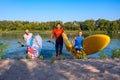 Joyful friends with SUP boards in their hands run out of the water Royalty Free Stock Photo