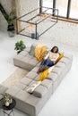 Joyful full of energy woman in casual clothes resting on the sofa, sitting on the couch in modern living room