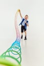 Joyful game. Boy, child in classical retro clothes playing with slinky toy over grey studio background. Concept of game