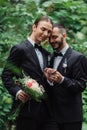 joyful gay couple in suits holding Royalty Free Stock Photo