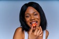 Joyful girl on a diet holds vivid ripe red strawberry in the mouth. Diet concept Royalty Free Stock Photo