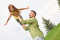 Joyful girl playing with her daddy in the green park, stretching out her hands, pretending flying. Young father holding