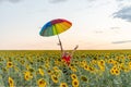 A joyful girl in sunglasses holds a colored umbrella at the top in a field of sunflowers Royalty Free Stock Photo