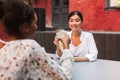 Joyful girl in white shirt drinking cocktails with friend while happily spending time in courtyard of cafe Royalty Free Stock Photo