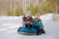 Joyful girls ride a tubing from a hill together. Winter holiday