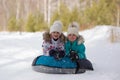 Joyful girls ride a tubing from a hill together. Winter holiday