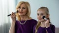 Joyful granddaughter and her granny applying face powder, preparing for party Royalty Free Stock Photo