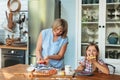 Joyful grandmother in casual clothes treating her granddaughter with freshly baked berry pie