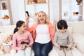 Joyful grandmother with cheerful grandchildren playing on game console sitting on couch. Royalty Free Stock Photo