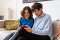 Joyful grandmother and grandson using smartphone together while sitting on sofa