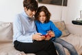 Joyful grandmother and grandson using smartphone together while sitting on sofa