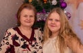 Joyful grandmother and granddaughter near the Christmas tree on New Year`s holidays. Royalty Free Stock Photo