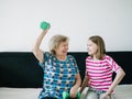 An elderly woman with her granddaughter is resting on the floor. Little happy girl exercising with her grandmother at Royalty Free Stock Photo