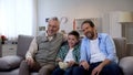 Joyful grandpa, father and son enjoying comedy show on tv, having fun together