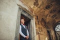 Joyful groom in elegant blue suit smiling and posing near old ca Royalty Free Stock Photo