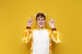 joyful guy in funny children\'s giraffe pajamas shows his hands up on yellow background, man in animal cosplay clothes