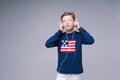 Joyful guy in wired headphones listens to music in blue sweater with us flag Royalty Free Stock Photo