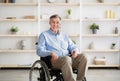 Joyful handicapped senior man in wheelchair smiling and looking at camera at retirement home Royalty Free Stock Photo