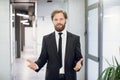 Joyful handsome bearded businessman, wearing stylish black suit, making welcoming gesture with his arms wide open and Royalty Free Stock Photo