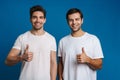 Joyful handsome guys smiling and showing thumbs up