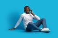 Joyful handsome young african guy listening to music on blue Royalty Free Stock Photo