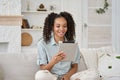Joyful happy African American pretty teenage girl using digital tablet at home. Royalty Free Stock Photo