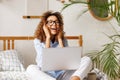 Joyful happy african american teenage girl feeling excited while sitting on bed with laptop Royalty Free Stock Photo