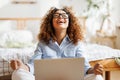 Joyful happy african american teenage girl feeling excited while sitting on bed with laptop Royalty Free Stock Photo