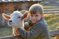 Joyful and happy boy hugs and strokes a horned goat, the concept of the unity of nature and man