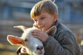 Joyful and happy boy hugs and strokes a horned goat, the concept of the unity of nature and man Royalty Free Stock Photo