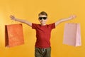 A joyful and happy buyer with colored bags in his hand shows his positive emotions from purchases. Baby with purchases on a yellow Royalty Free Stock Photo