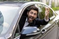 Joyful and happy car driver smiling and looking at camera, mature businessman waving his hand in greeting gesture, boss Royalty Free Stock Photo