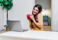 Joyful happy cheerful young woman enjoying warm cup of coffee at home while using laptop smiling girl drinking warm tea or hot Royalty Free Stock Photo