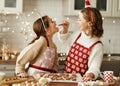Joyful happy family mother and girl daughter having fun while baking christmas cookies in kitchen