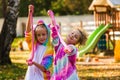 Joyful happy girls in rainbow costumes play slime. Girls walk in the park in uniforms. Children with slime