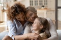 Three generation family little girl mom grandma tickle on sofa